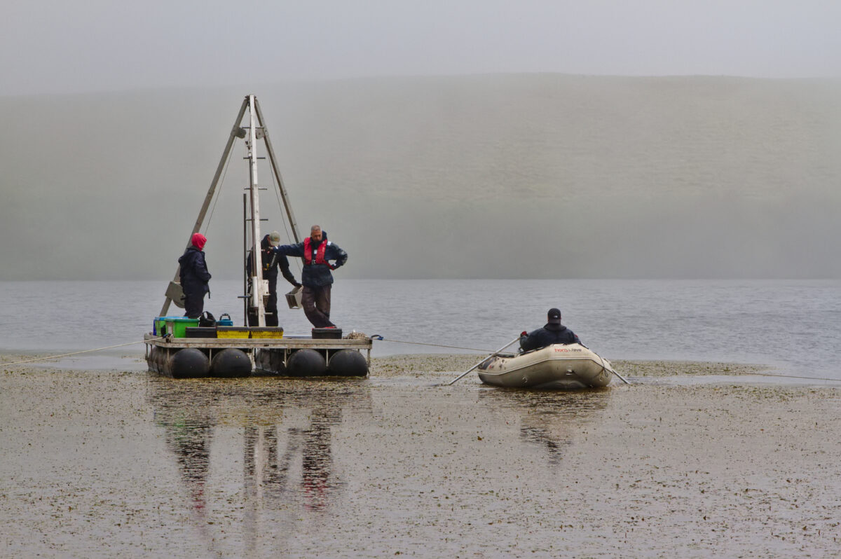 Toma de muestras en el lago Lomba donde se aprecia el crecimiento de plantas en la superficie (Santiago Giralt)